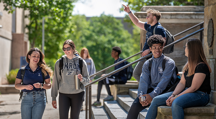 Happy ϲ students walking out of and in front of Buchtel Hall on The University of Akron campus.